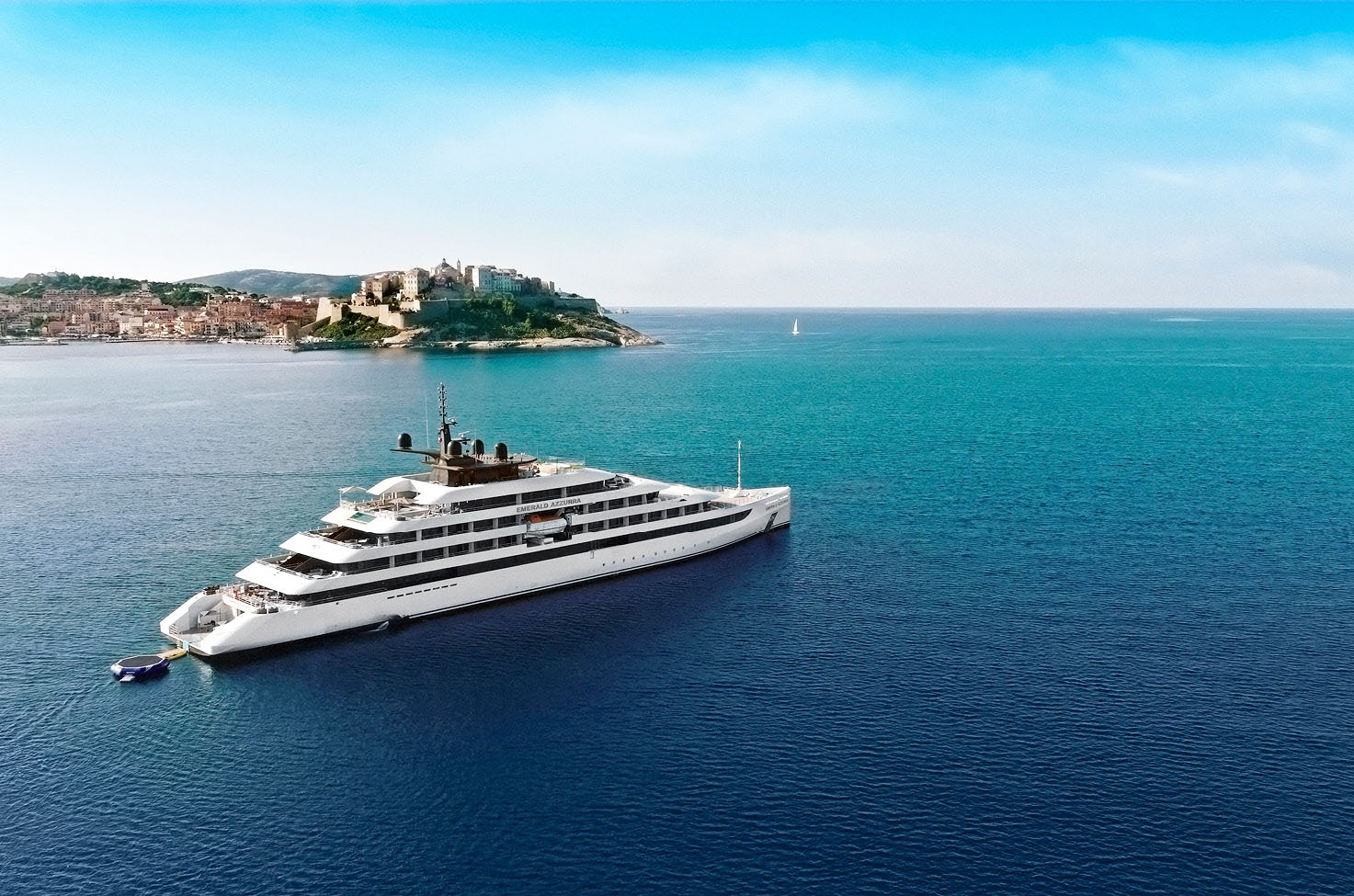 Luxury yacht on calm blue sea sailing past Corsica, under a blue, light cloudy sky